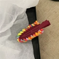 Dettaglio di un fermaglio per capelli rosso avvolto in filati colorati su carta velina - Borgogna