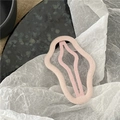 Dettaglio di un fermaglio per capelli rosa vellutato ondulato su sfondo minimalista - Rosa