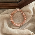 Detailed macro view of woven pink and brown knit hair tie on soft beige linen fabric - Orange Pink
