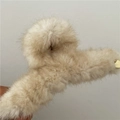 Dettaglio della pinza per capelli in pelliccia sintetica beige con emblema dorato - Bianco avorio
