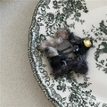 Dettaglio del fermaglio a stella in peluche con trama in lana mista e inserto dorato - Etichetta Dorata Stella / Nero Iridescente