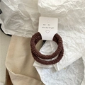 Primer plano de gomas de pelo elásticas marrón café en una tarjeta de estilo minimalista - Café Oscuro Plisado
