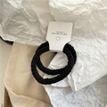Primer plano de dos gomas de pelo de felpa negra en una tarjeta blanca de presentación - Plisado Negro