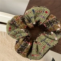 Dettaglio ravvicinato dello scrunchie in tweed multicolore con trama intrecciata e quadri - Verde