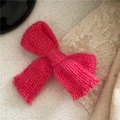 Detail shot of a hand-knitted rose pink bow hair clip with textured wool pattern - Rose Red