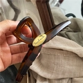 Close-up of tortoise shell hair claw clip featuring a golden handmade metal plaque - Large Cross (Yellow-Green Leopard)
