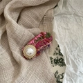 Close-up of a handmade woven bow hair clip with a vintage pearl and golden metal center - Oval