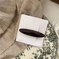 Gros plan d'une barrette en acétate marron foncé sur carte blanche avec fond floral rétro - Café Foncé