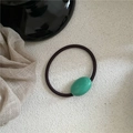 Macro view of a dark brown elastic hair tie featuring a smooth green oval resin bead - Oval Rubber Band / Mint Green (Lacquer)