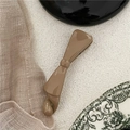 Detailed view of glossy brown plastic bow banana hair clip on vintage ceramic plate - Light Coffee