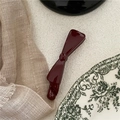 Deep red bow banana hair clip on a minimalist textured surface with vintage aesthetic - Burgundy