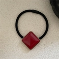 Close-up of red geometric resin square with gold metallic trim on a black elastic hair tie - Red