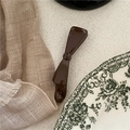 Detailed view of coffee brown bow banana hair clip on vintage fabric and ceramic plate - Dark Coffee