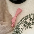 Pink bow banana clip with a glossy glaze finish on a rustic fabric background - Pink