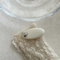 Nahaufnahme der creme-ovalen Haarspange mit Silberherz auf Strickstoff-Hintergrund - Herzform / Silberherz Weiße Klammer