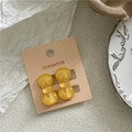 Detail view of amber resin bow earrings displayed on a premium retail card - Yellow