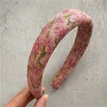 Gros plan détaillé d'un serre-tête rose à fleurs avec texture en velours côtelé - Rose (Imprimé)