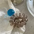 Dettaglio dell'elastico a spirale marrone traslucido con una perla rotonda blu brillante - Blu