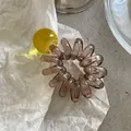 Dettaglio dell'elastico per capelli a spirale con perla gialla su sfondo bianco - Giallo