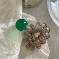 Dettaglio dell'elastico per capelli a spirale marrone con una grande perla verde smeraldo lucida - Verde