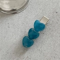 Nahaufnahme von drei blauen Marmor-Herz-Haarklammern auf strukturiertem Stein - Blau
