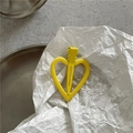 Vue détaillée d'une pince à cheveux jaune en forme de cœur sur un fond minimaliste chic - Jaune