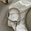 Detail of silver beaded bracelet with bow pendant on a textured stone surface - Bowknot Hair Tie