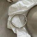 Close-up of polished silver mirror beads arranged on an artistic textured surface - Single Beaded Hair Ring