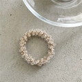 Makro-Detail von Kristall-Haargummi mit champagnerfarbenen facettierten Perlen auf Textur - Transparent