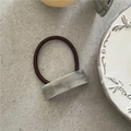 Close-up of marble texture resin hair tie with golden lettering on grey stone background - Gray