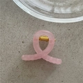 Detailed macro view of a translucent pink jelly hair claw clip with golden metal spring - Pink