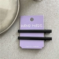 Détail de deux barrettes rectangulaires noir brillant sur une carte d'exposition mauve - Noir