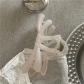 Dettaglio dell'elegante pinza per capelli a fiocco perlato su sfondo materico - Bianco Trasparente