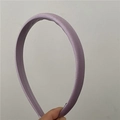 Dettaglio di un cerchietto minimalista in raso color lavanda con trama liscia in tessuto - Viola