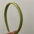 Dettaglio ravvicinato di un cerchietto in raso verde erba che mostra la sua trama setosa - Verde