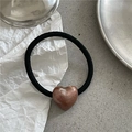 Detail of a black elastic hair tie with a brown metallic heart charm on a gray surface - Brown Heart (Hair Tie)
