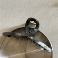 Dettaglio della molletta per capelli marmorizzata con molla dorata su pietra - Trama Marmo Nero (B6.1)