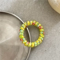 Macro shot of yellow spiral hair tie with colorful graffiti patterns on metal tray - Colorful Red Yellow