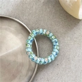 Detailed macro of a light blue floral spiral hair tie on a decorative silver tray - Multicolor Blue