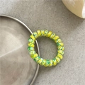 Macro detail of yellow graffiti spiral hair tie on a decorative metal tray edge - Colorful Green Yellow