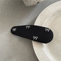 Close-up of black fabric snap clip with silver bow charms on a ceramic textured surface - Black Bow Style (E4.3)