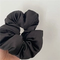 Dettaglio macro di un elastico in raso nero che mostra la consistenza liscia e lucida - Nero