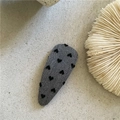 Dettaglio di un fermaglio per capelli in tessuto grigio con motivi a cuore nero su pietra - Goccia Corta Cuore Grigio