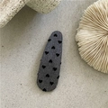 Dettaglio del fermaglio ovale BB con tessuto grigio e motivi a cuore nero floccato - Goccia Lunga Cuore Grigio
