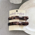 Detailed macro view of two tortoiseshell leopard print hair clips on a textured stone surface - White Leopard