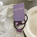 Dettaglio di elastici per capelli a cuore viola con strass su un vassoio bianco - Viola