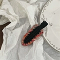 Détail de barrettes à cheveux en laine tricotée colorée sur une assiette en céramique - Noir