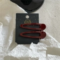 Close-up of burgundy drop-shaped metal hair clips on a decorative black handmade card - Water Drop Style