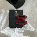 Close-up of two deep red oval hair clips on a black handmade gift card display - Hollow Oval Style