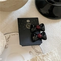Dettaglio di due fermagli neri lucidi fatti a mano con perle rosse su cartoncino - Paio di clip / Nero